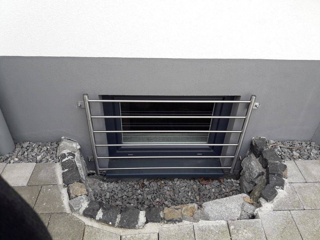 ein Fenster mit einem Edelstahlgitter an der Seite eines Gebäudes.