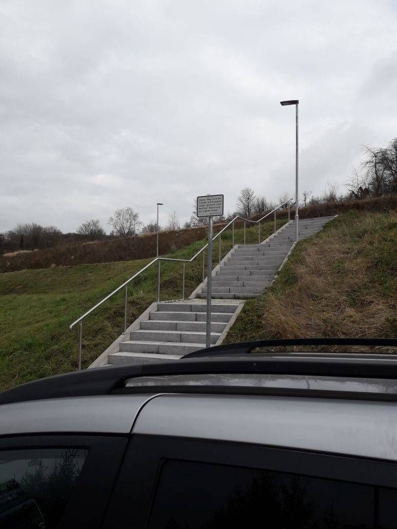 Ein Auto parkt neben einer Treppe, die einen Hügel hinaufführt.