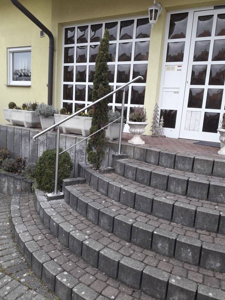 Eine Treppe, die zu einem Gebäude mit einem Geländer aus Edelstahl führt