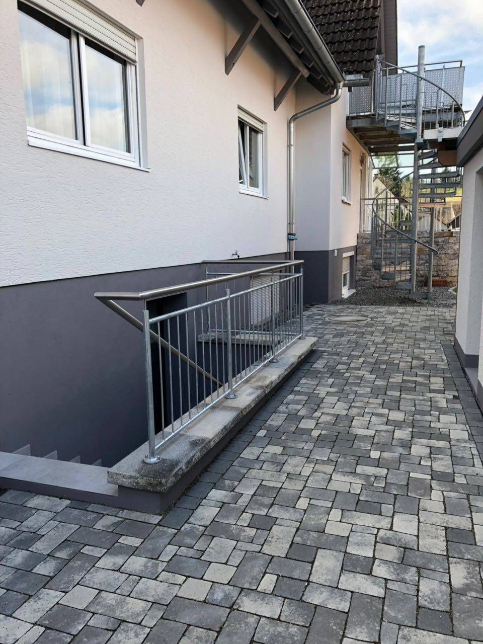 Ein gemauerter Gehweg, der zu einem Haus mit Treppen und Geländer führt