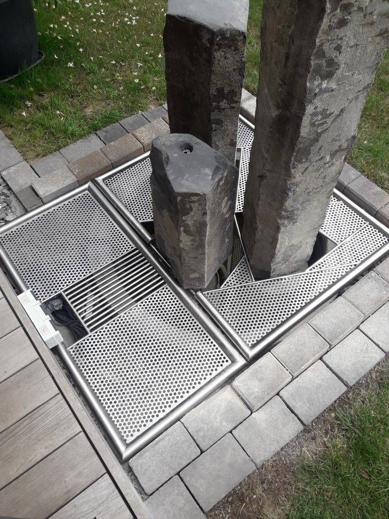 Eine Statue steht auf einem gemauerten Gehweg neben einem Metallgitter.