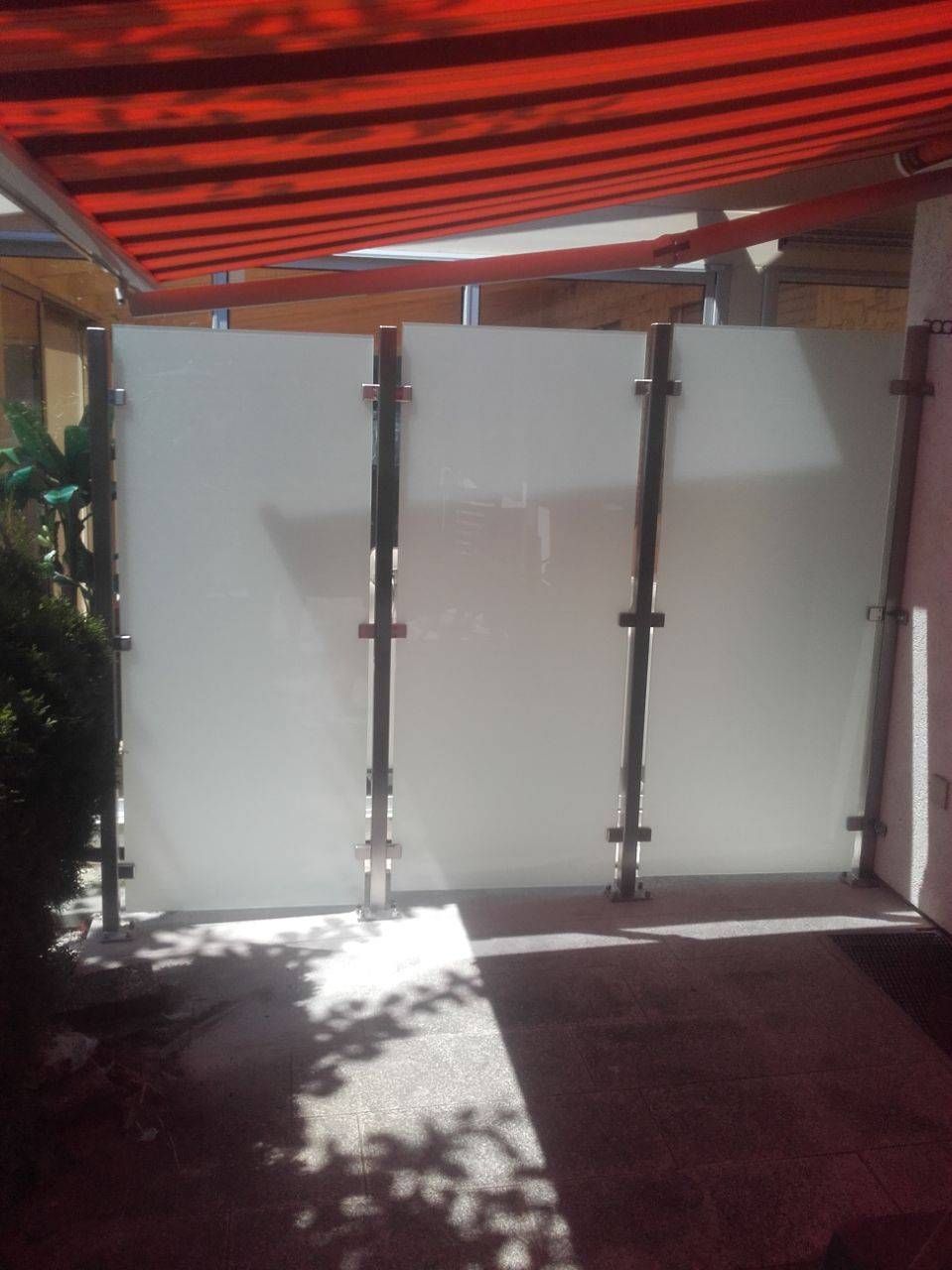 Eine rote Markise hängt über einer weißen Wand