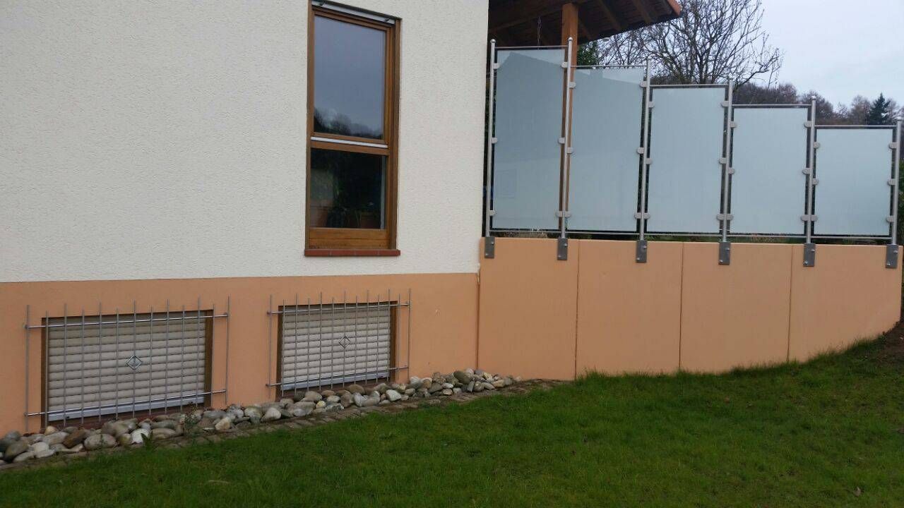 ein Haus mit einem Zaun und einem Fenster an der Seite.