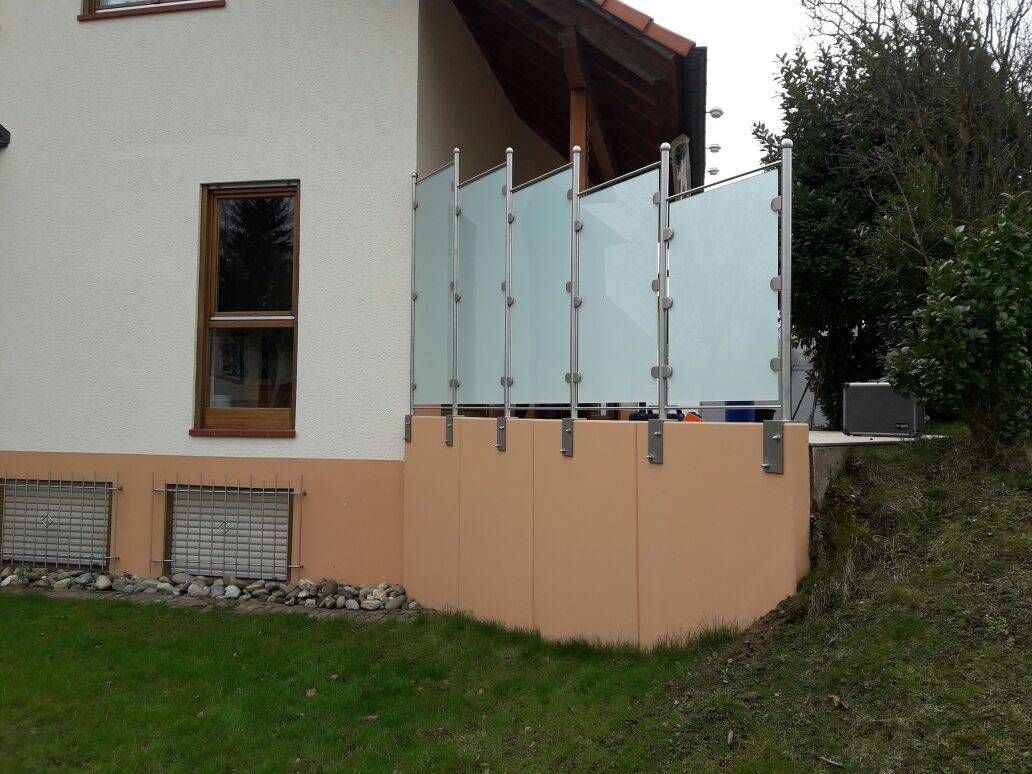 ein weißes Haus mit einem Glaszaun drumherum