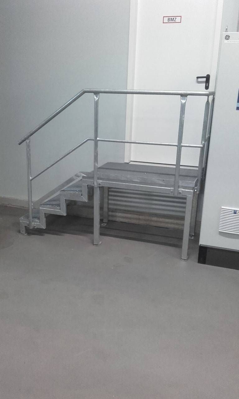 eine Metalltreppe mit Geländer in einem Raum neben einer Tür.