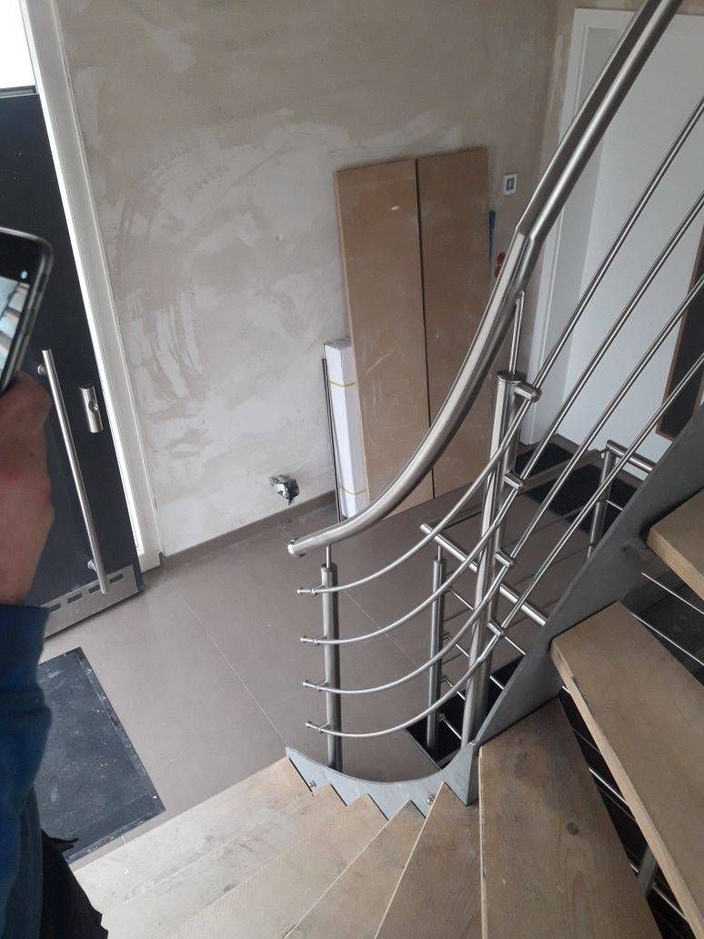 Eine Person fotografiert eine Wendeltreppe mit einem Edelstahlgeländer.