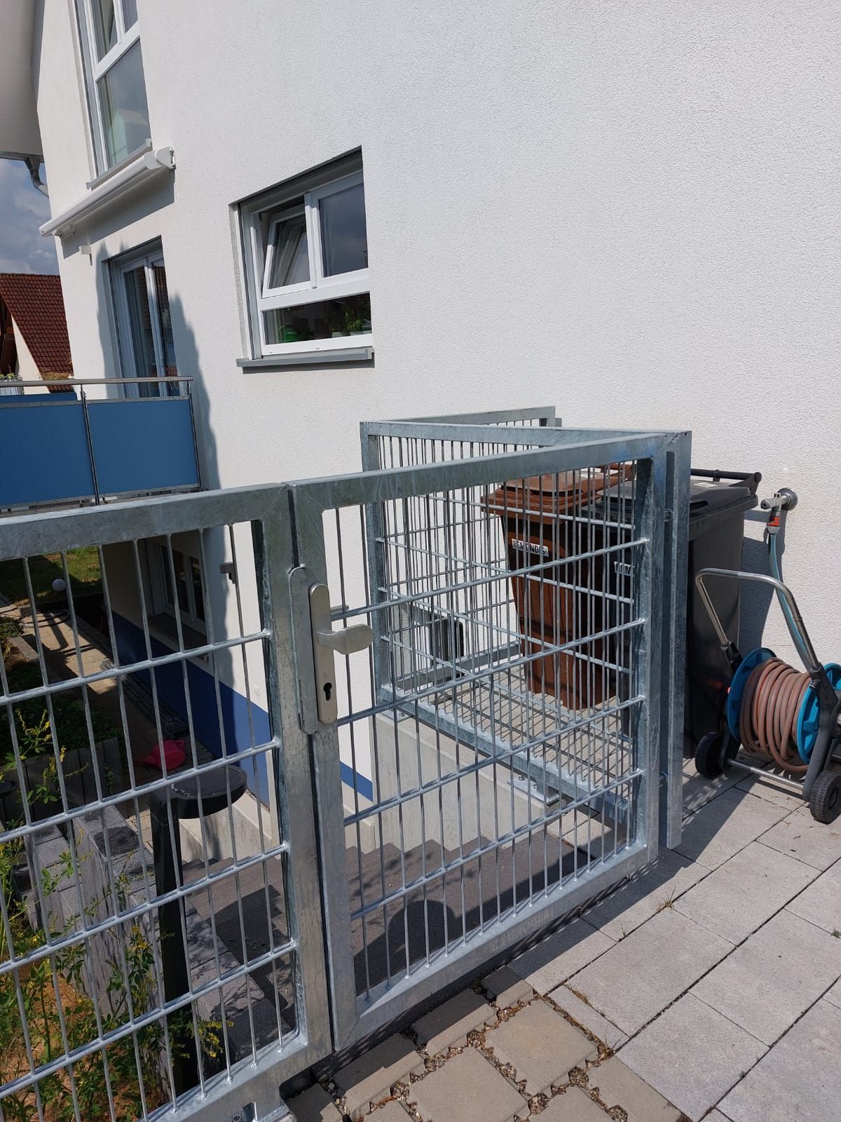 Ein Metallzaun umgibt einen Balkon, zu dem eine Treppe hinaufführt.