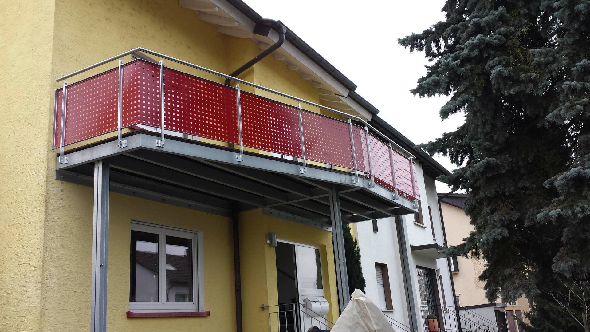 ein gelbes Haus mit einem roten Balkon an der Seite
