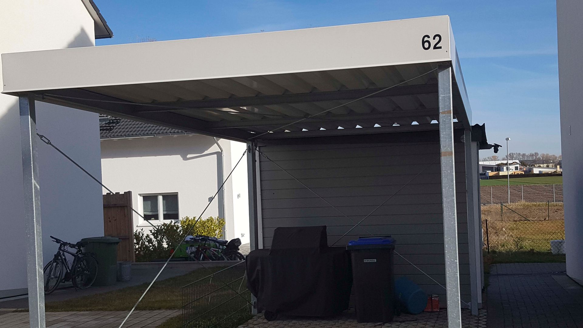 Vor einem Haus steht ein Carport mit der Nummer 62.