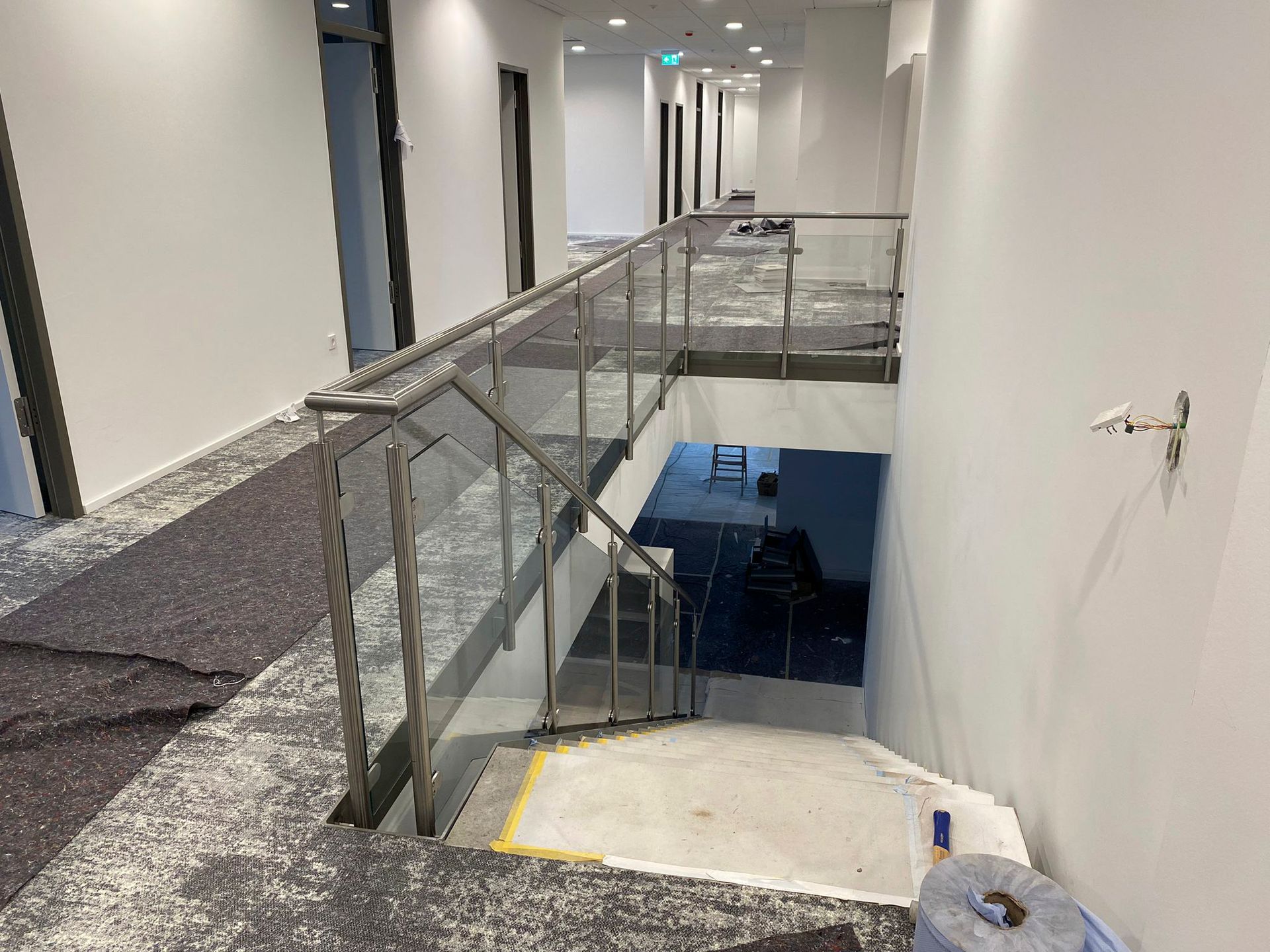 Eine Treppe mit einem Glasgeländer in einem im Bau befindlichen Gebäude.