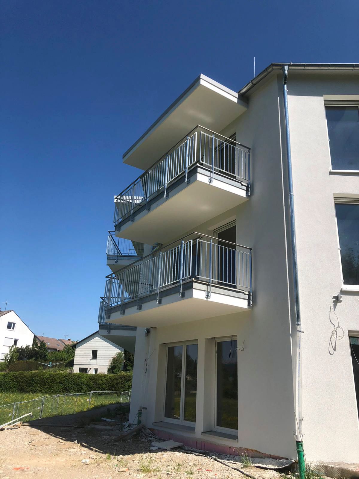 ein weißes Gebäude mit Balkonen und einem blauen Himmel im Hintergrund