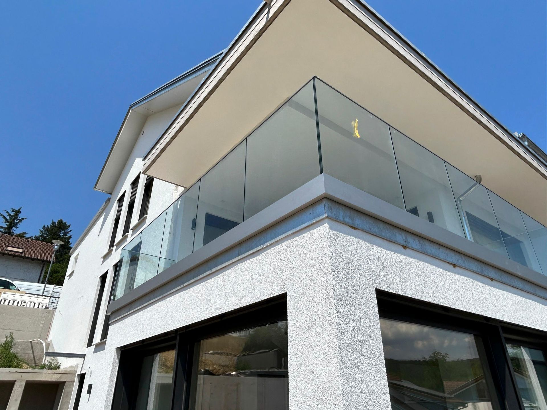 ein weißes Haus mit einem Glasgeländer auf dem Balkon