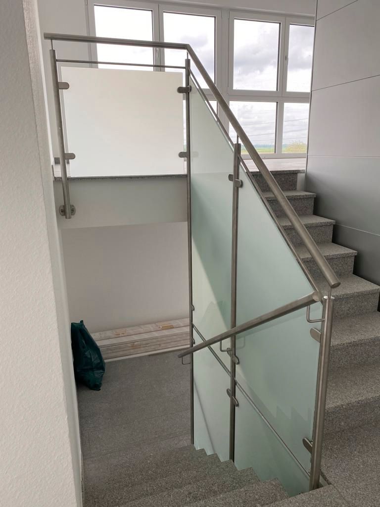 eine Treppe mit einem Edelstahlgeländer und einem Glasgeländer