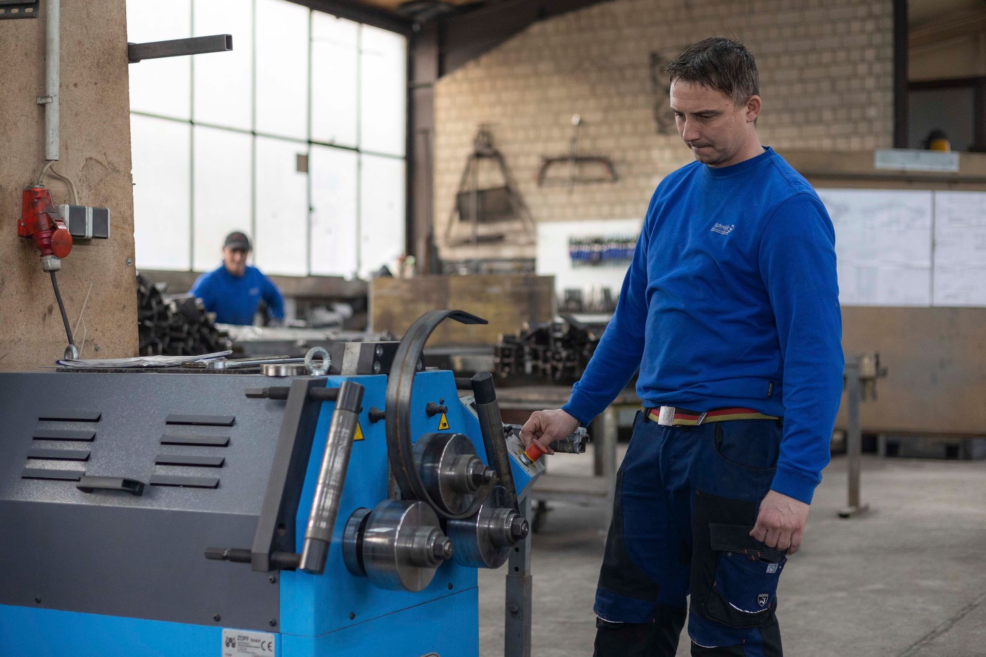 Ein Mann in einem blauen Hemd arbeitet an einer Maschine in einer Fabrik.