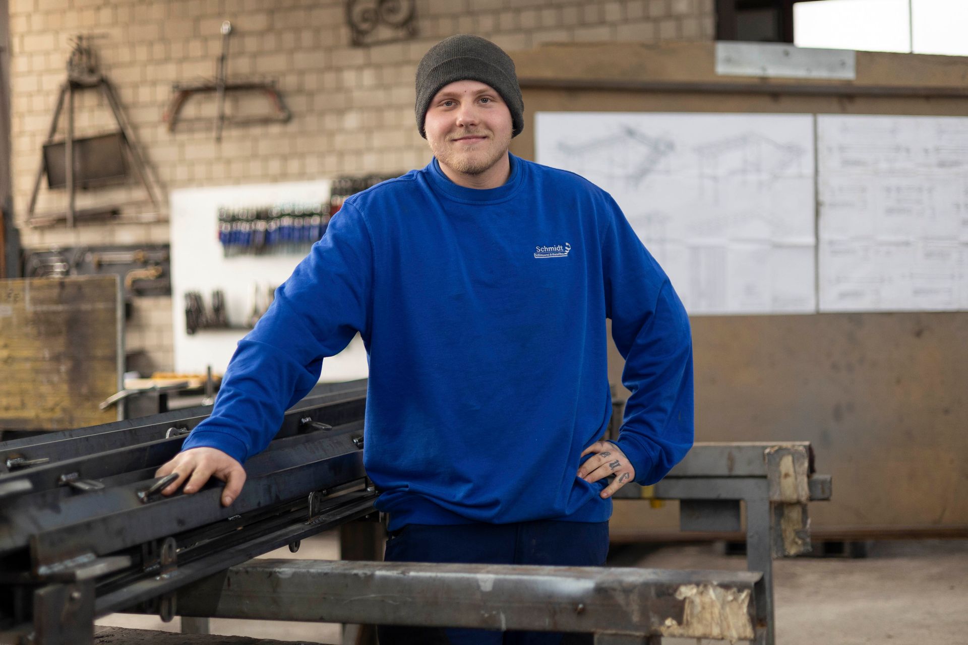 Ein Mann in blauem Hemd und Hut steht in einer Fabrik.