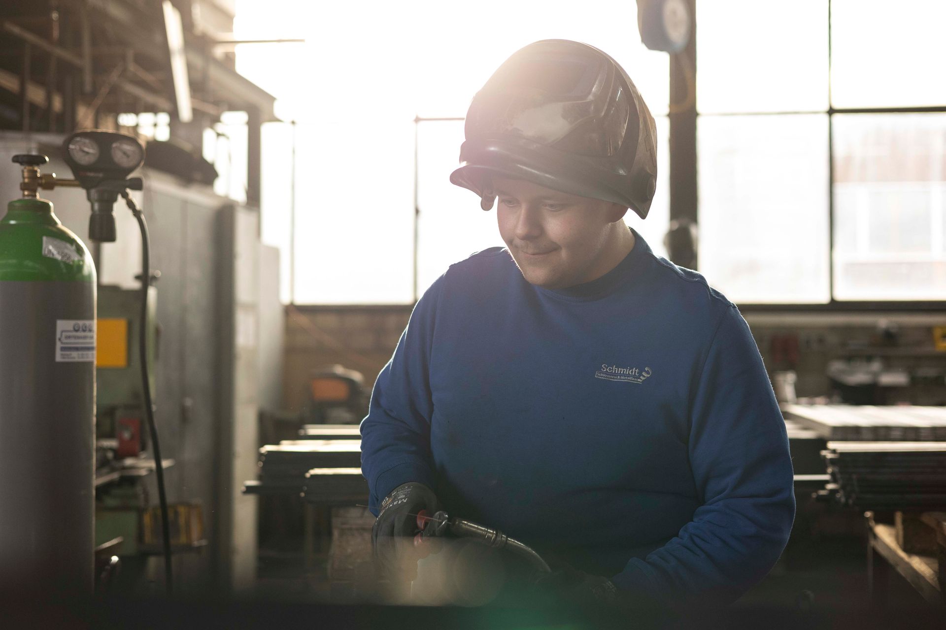 Ein Mann mit Helm schweißt in einer Fabrik ein Stück Metall.