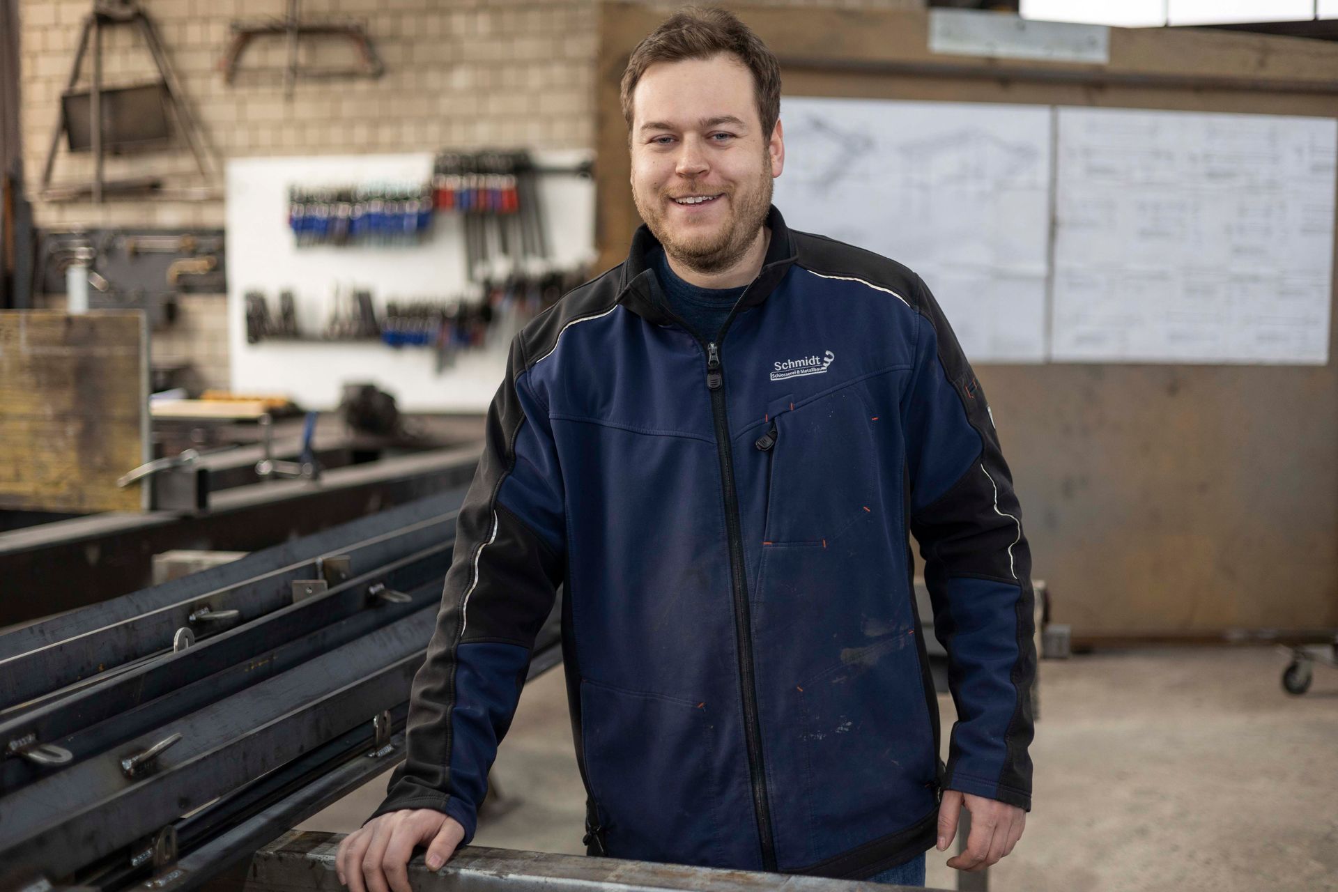 Ein Mann in einer blauen Jacke steht in einer Fabrik.