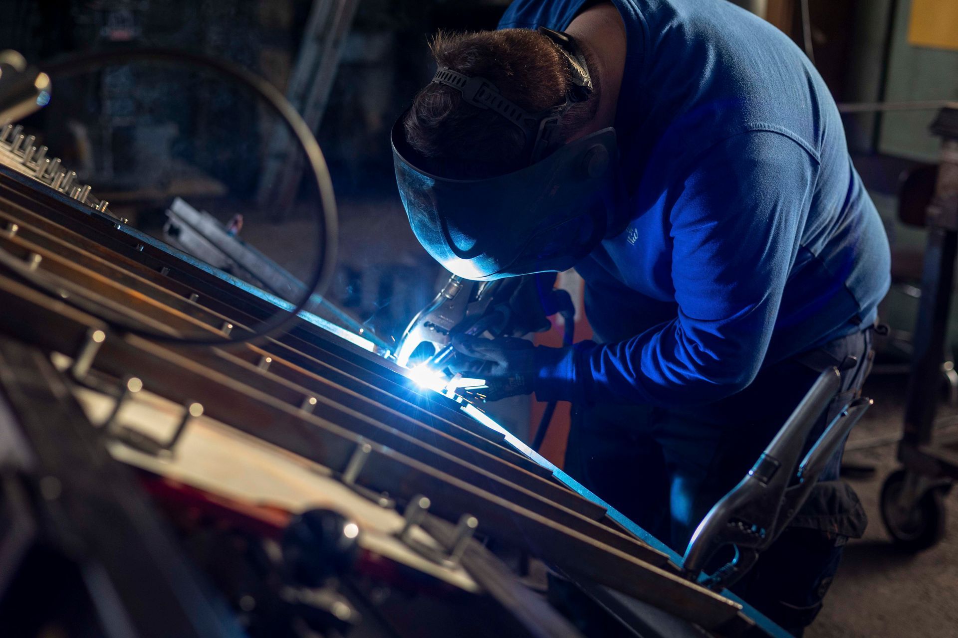 Ein Mann schweißt in einer Fabrik ein Stück Metall.