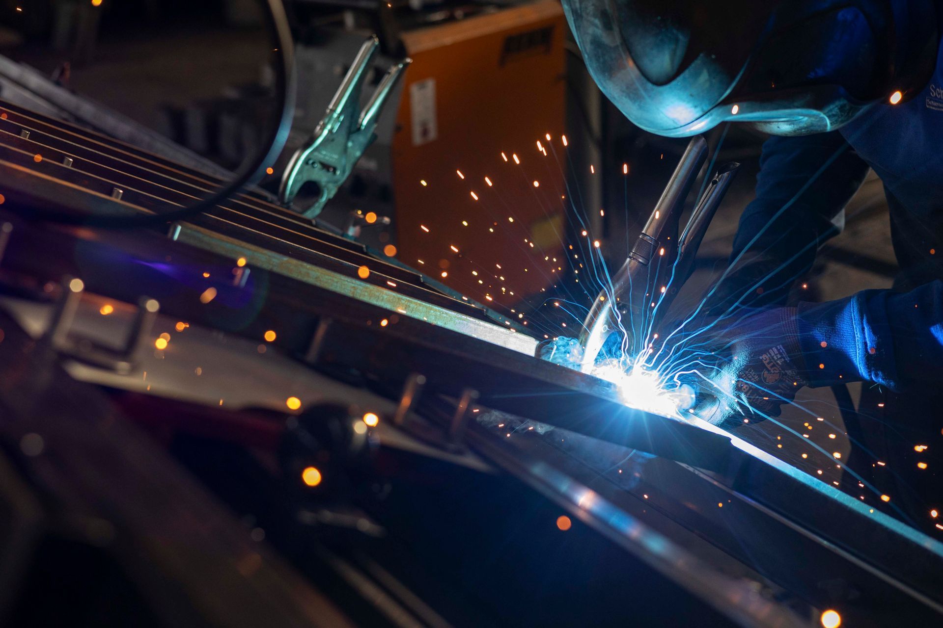 Ein Mann schweißt in einer Fabrik ein Stück Metall.