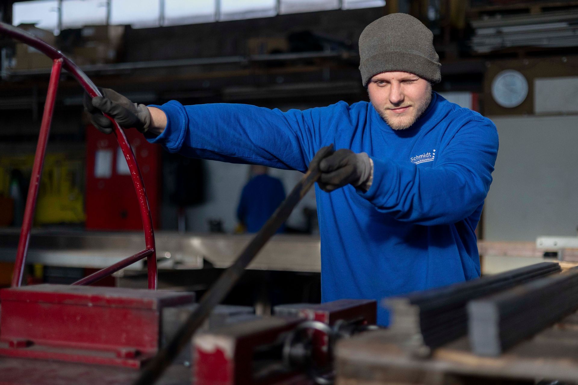 Ein Mann in einem blauen Hemd arbeitet an einer Maschine in einer Fabrik.
