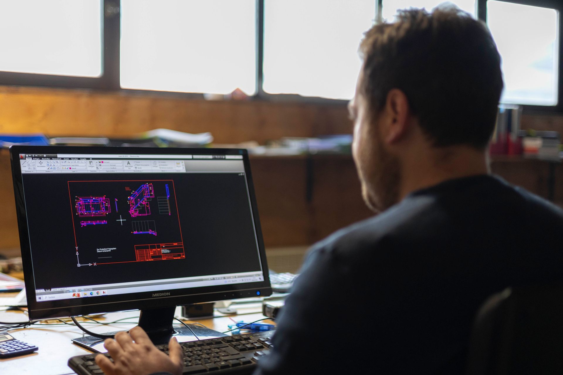 Ein Mann sitzt an einem Schreibtisch und schaut auf einen Computerbildschirm.