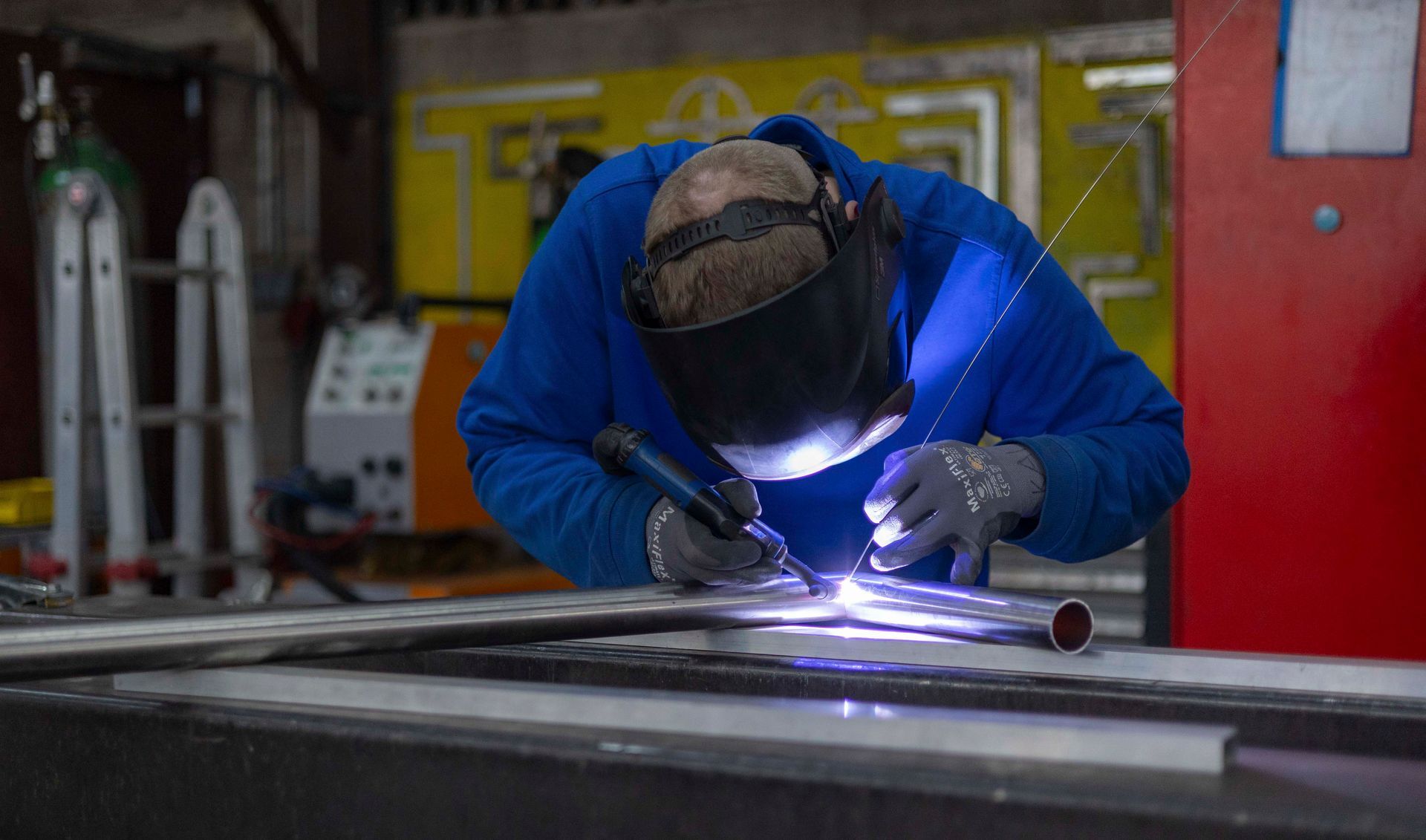 Ein Mann schweißt in einer Fabrik ein Stück Metall.