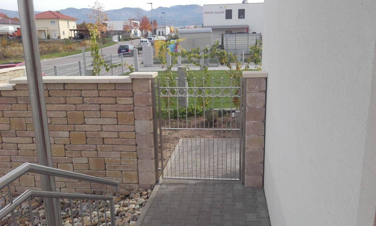 eine Treppe, die zu einem Tor vor einer Backsteinmauer führt.