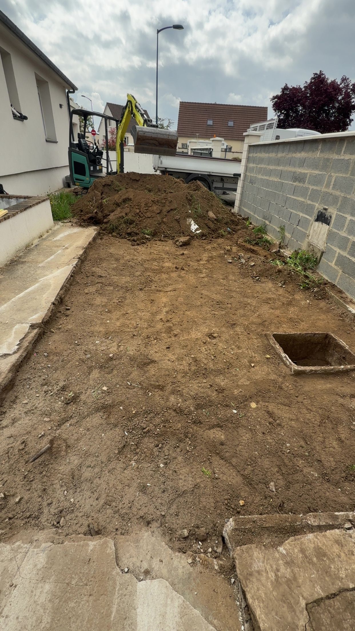 Création d'une terrasse : béton fraîchement coulé avec coffrage en bois, près d'un jardin.