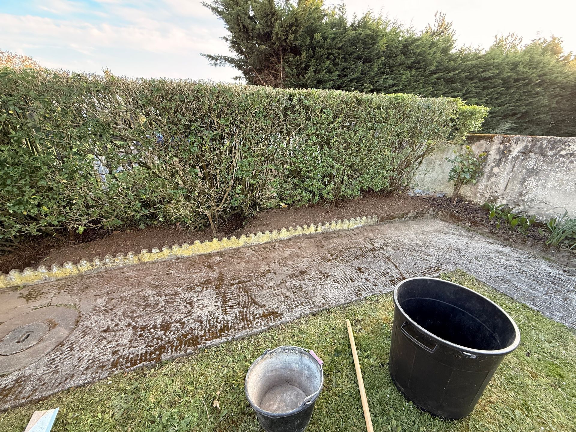 Massif de jardin récemment entretenu avec haie taillée et terre fraîchement travaillée.