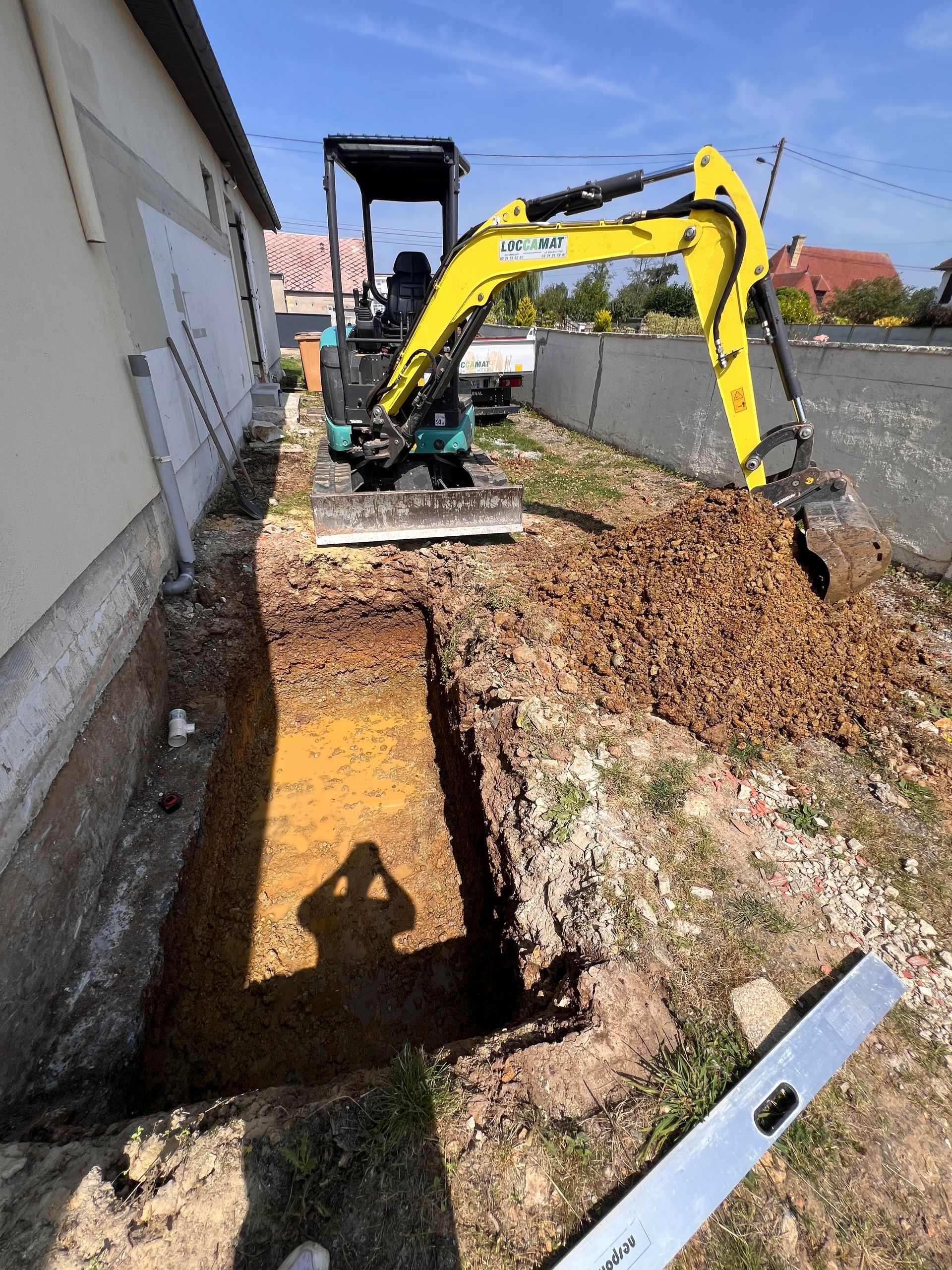 Jardin résidentiel en travaux avec délimitation de fondations et engins de chantier.