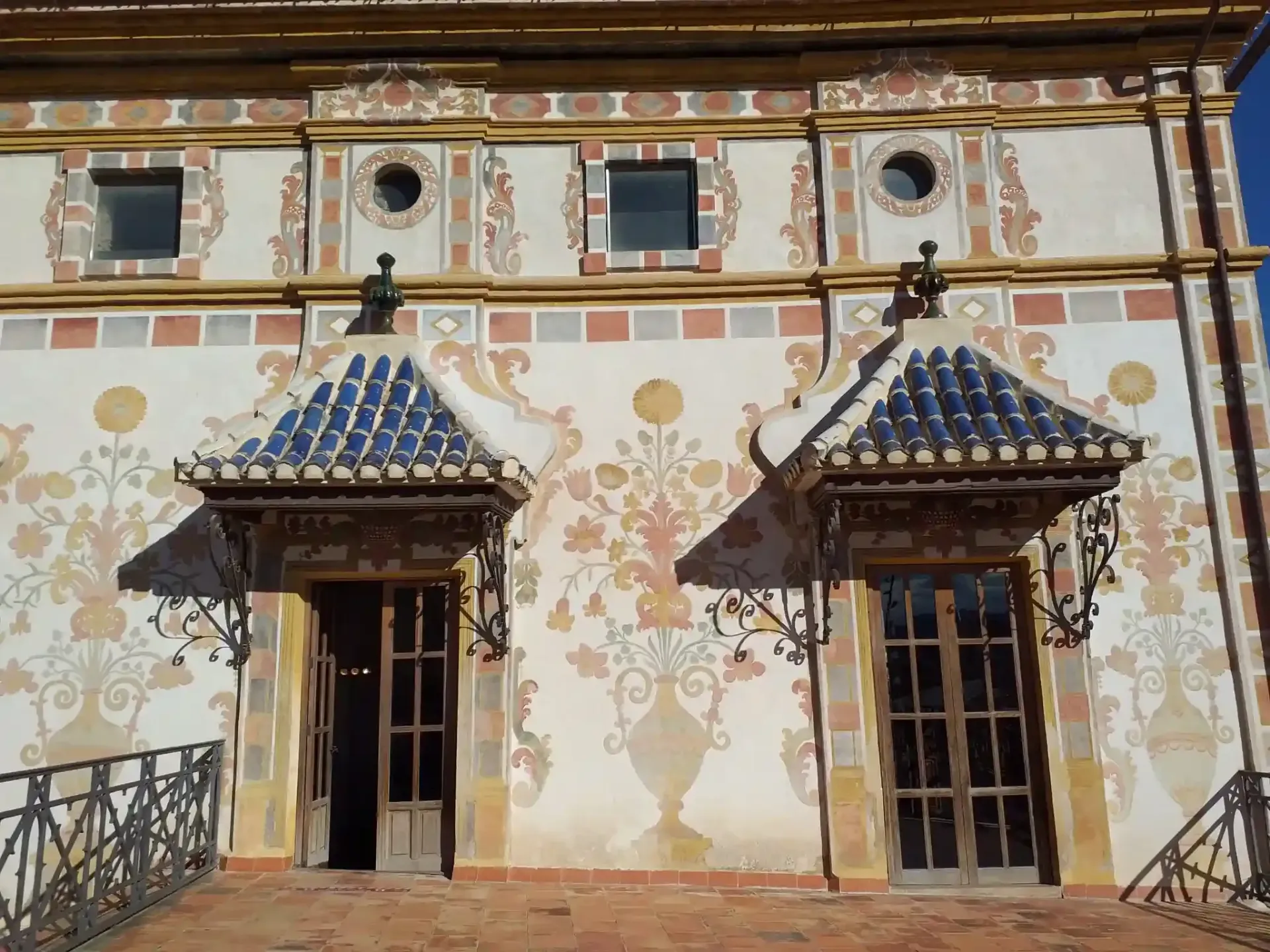 Fachada histórica decorativa con dos entradas de azulejos azules y paredes de yeso con motivos decorativos.