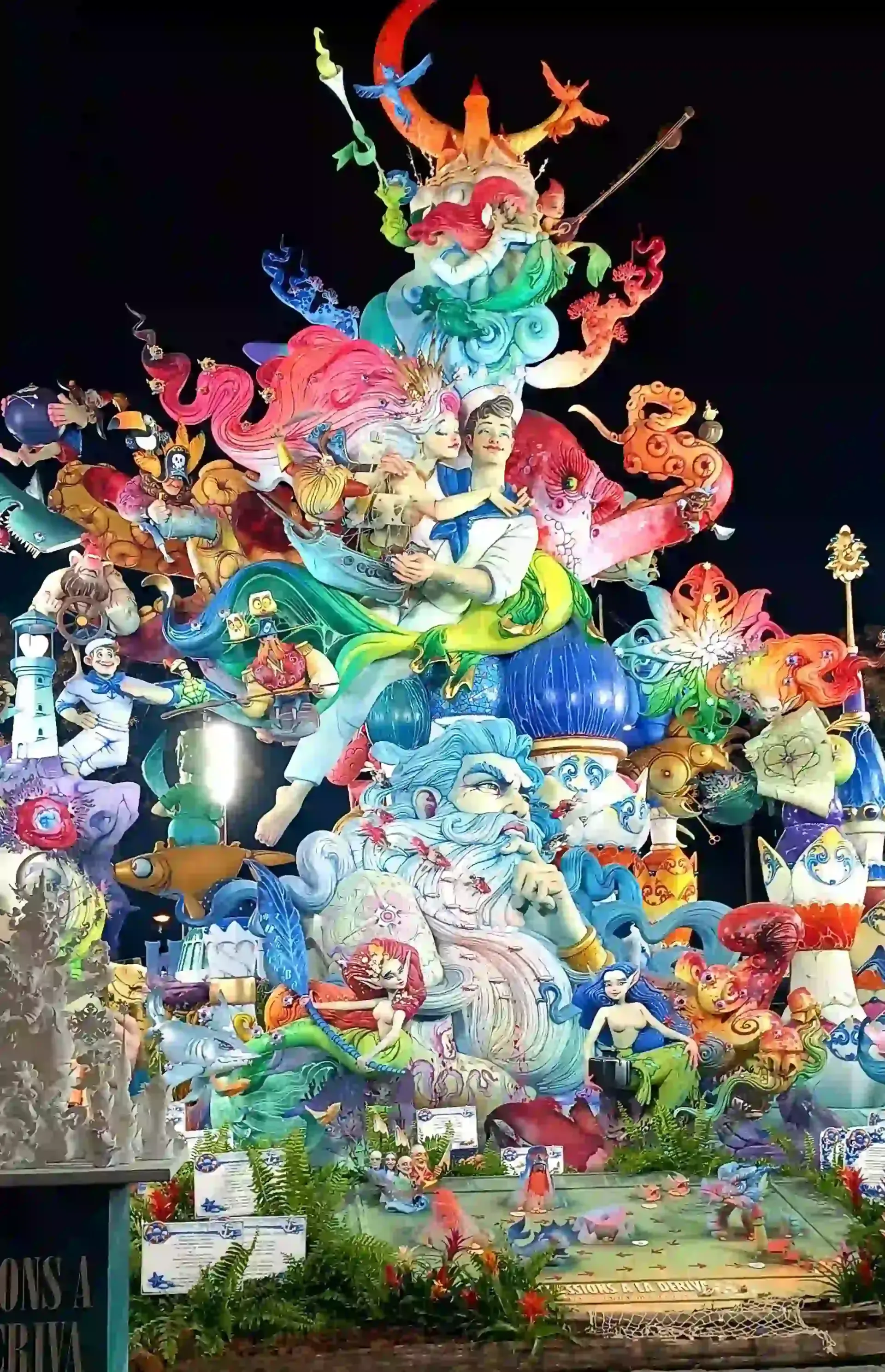 Decoración navideña colorida y original con una escultura luminosa en forma de árbol y figuras de animales divertidas por la noche.