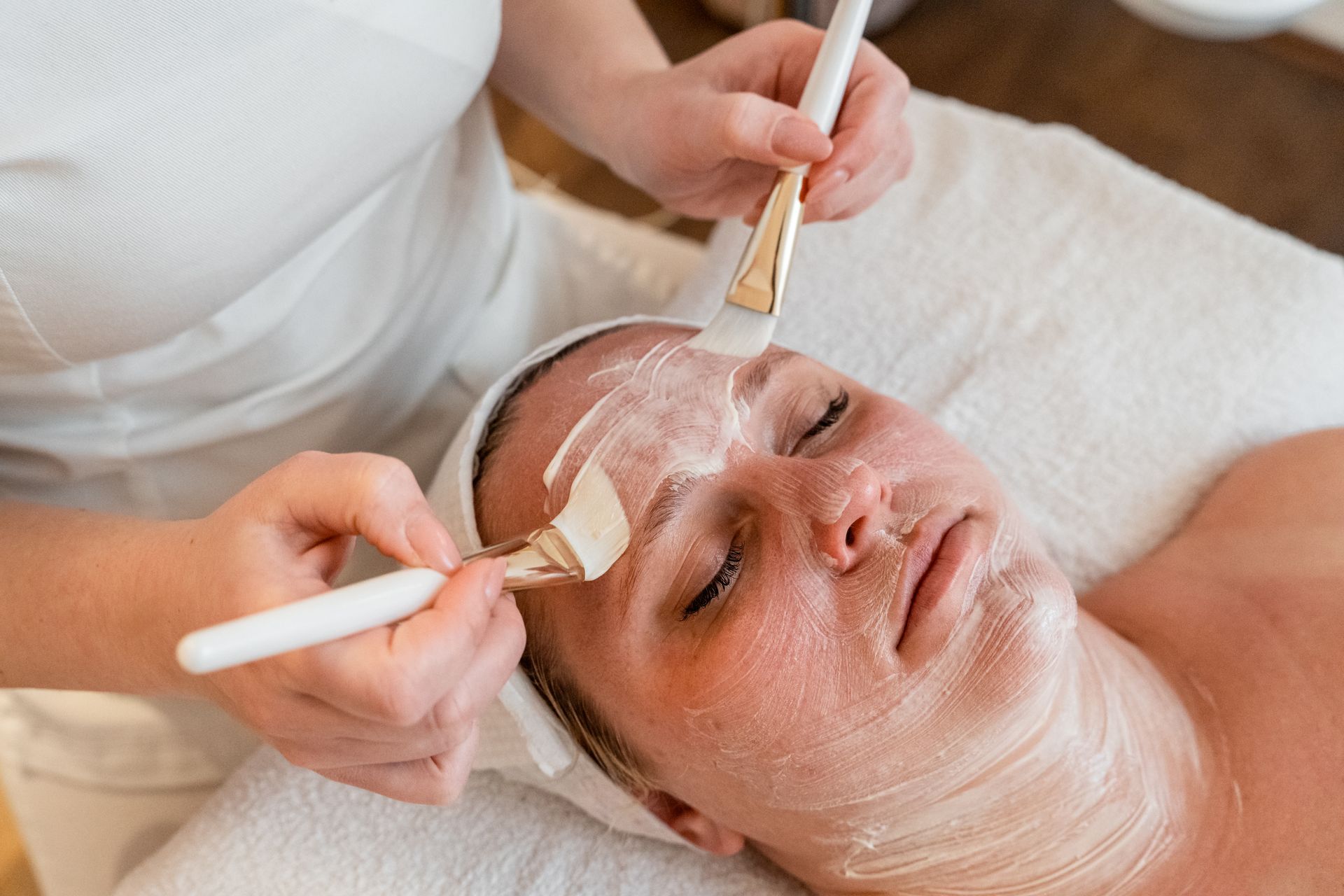 Soin du visage en institut avec masque crème appliqué au pinceau