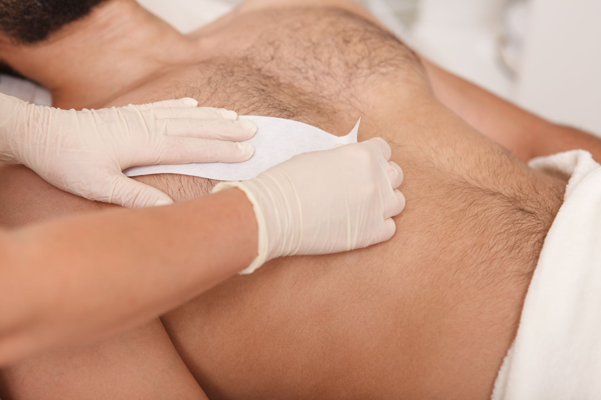 Des mains gantées effectuent un examen abdominal médical sur un patient allongé