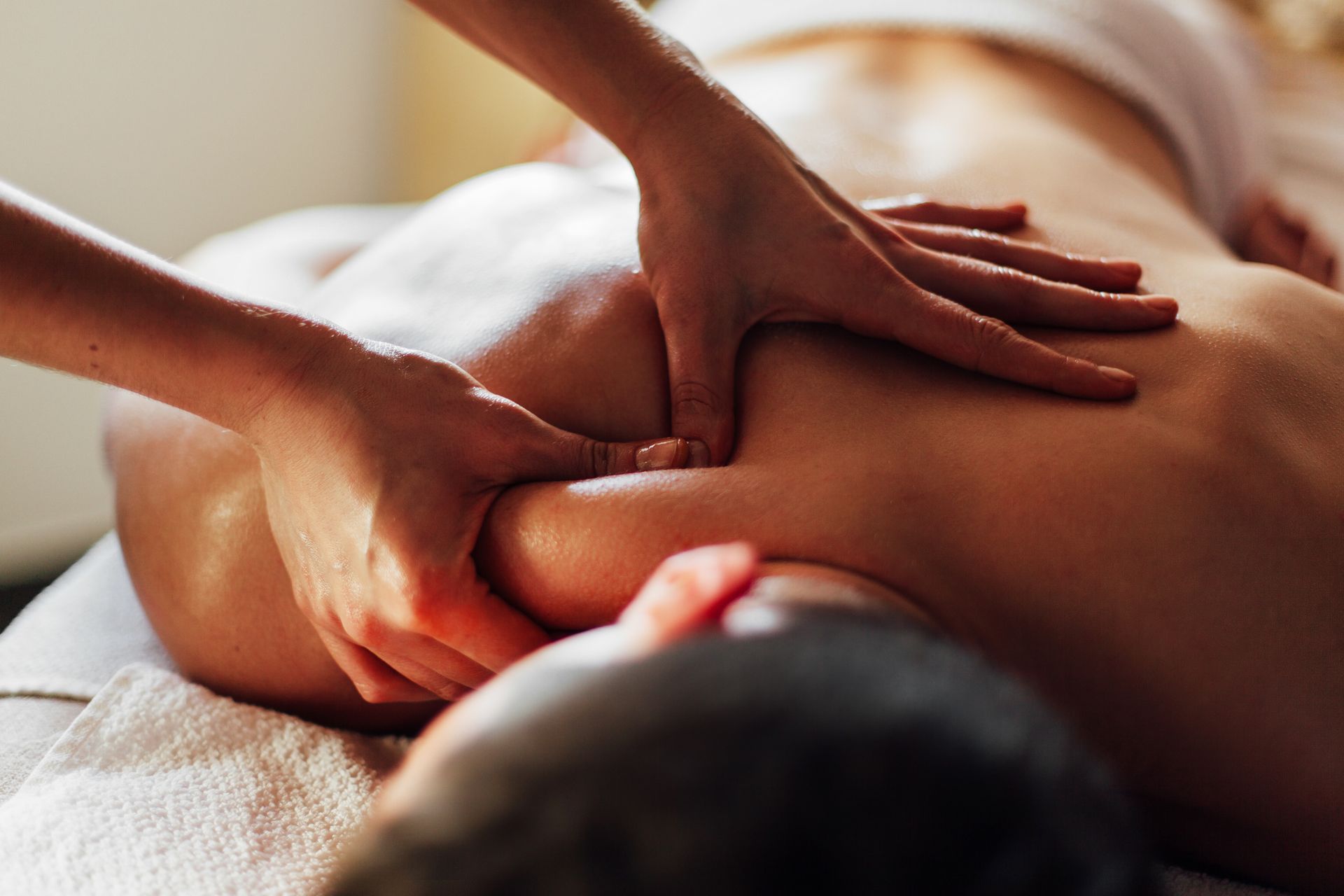 Mains massant le dos d'une personne allongée sur le ventre sur une table de massage