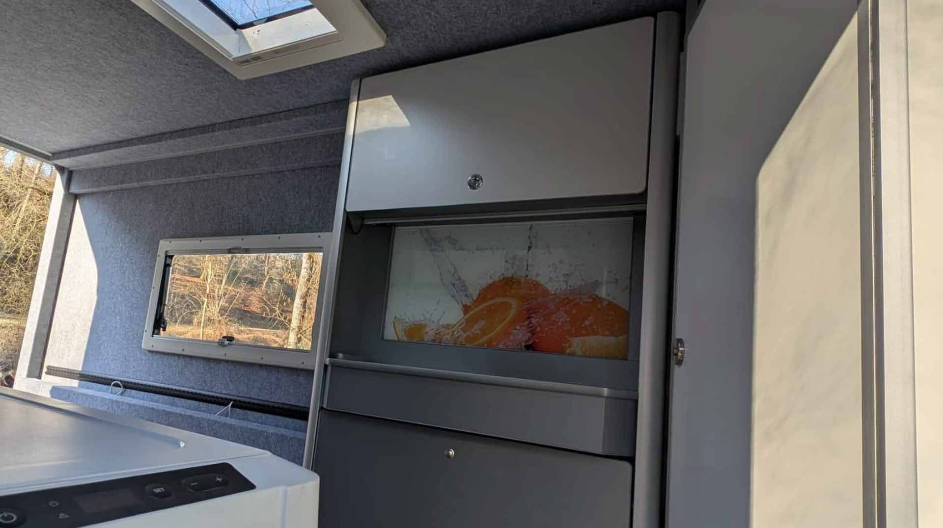 Das Innere eines Wohnmobils mit Herd und Fenster.