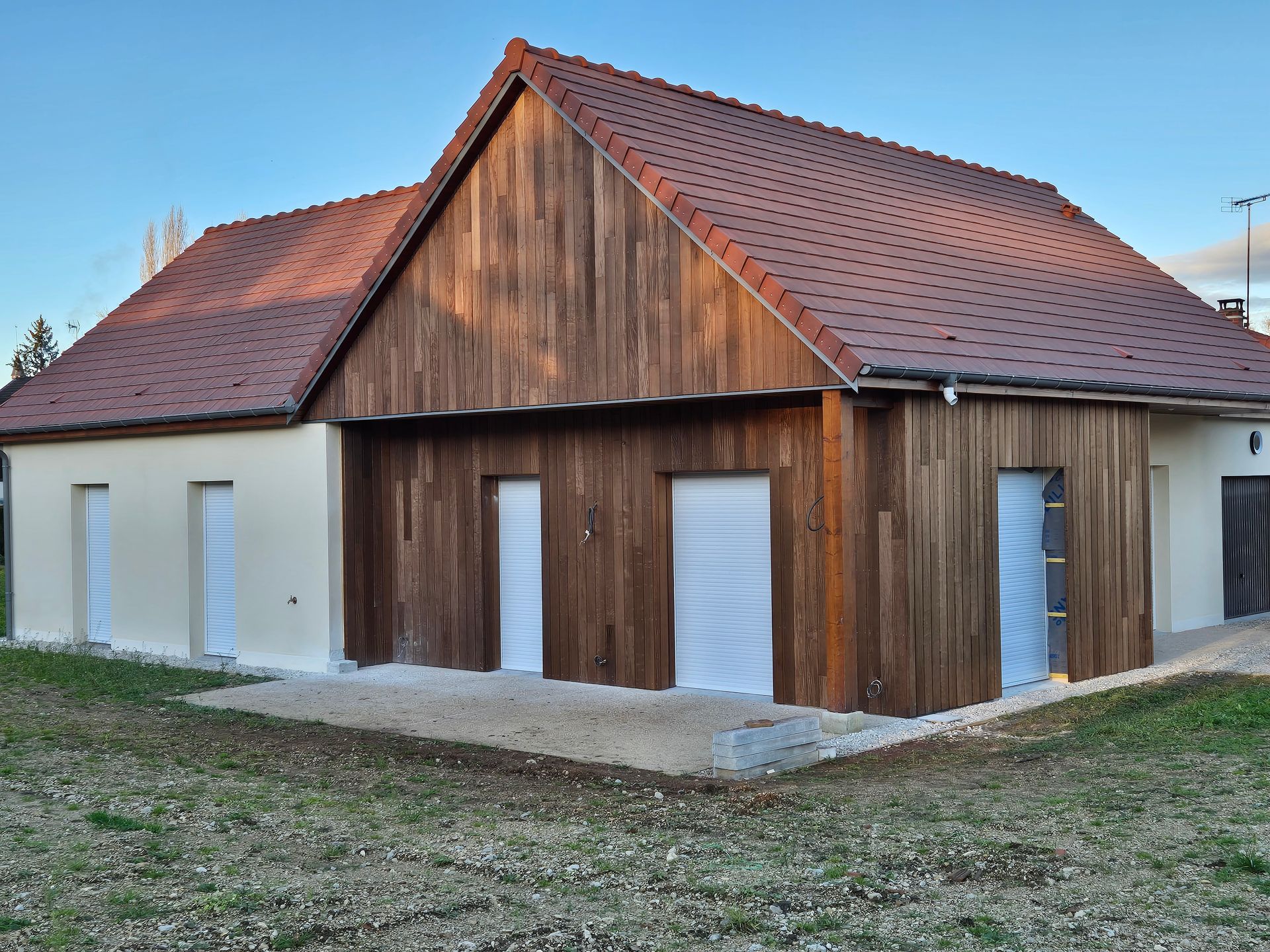 Un bâtiment de deux étages avec une façade en bois brun, des murs beiges et un toit de tuiles rouges, situé en extérieur.
