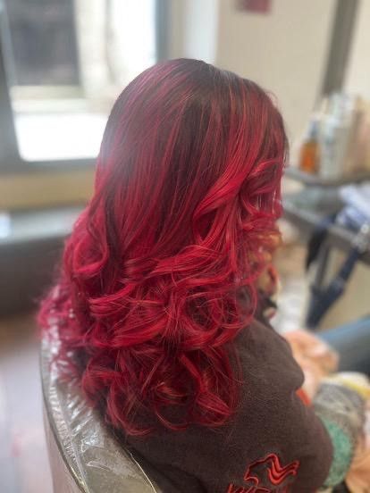 Donna con i capelli ricci e rossi vivaci seduta sulla poltrona di un salone di bellezza.