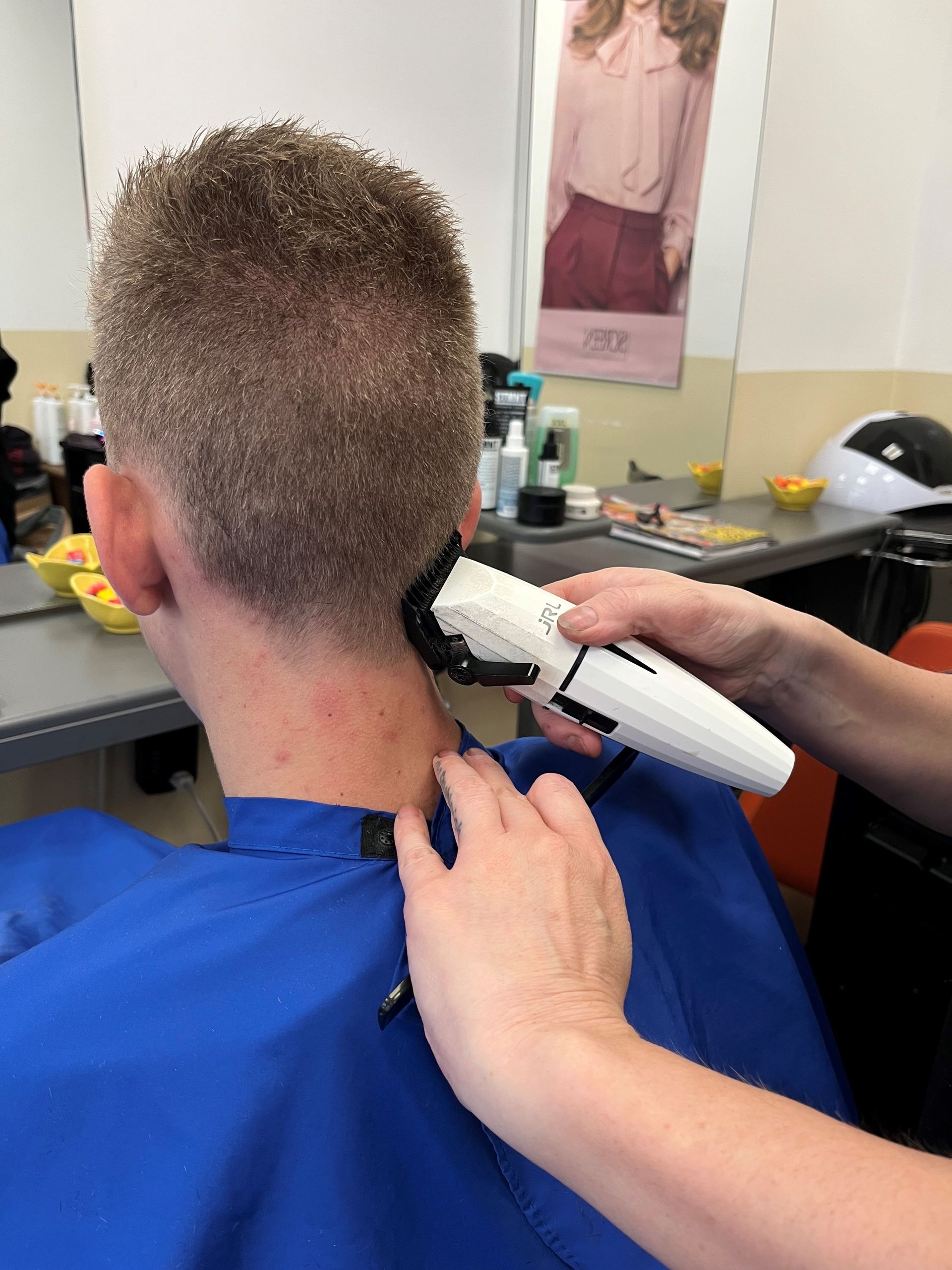 Persona che si fa tagliare i capelli con il tagliacapelli; capelli castani, sfumati corti. 