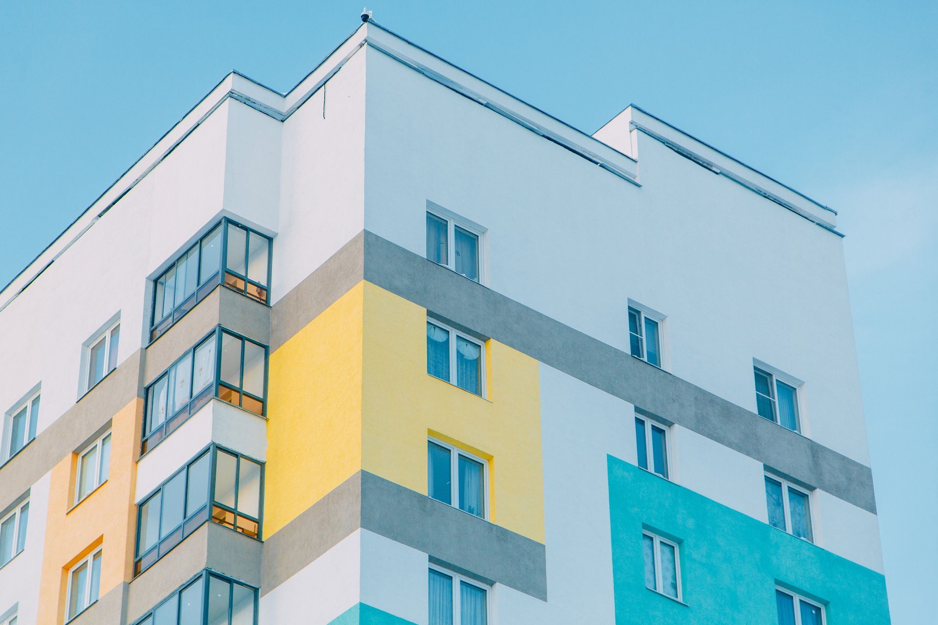Un edificio alto con una fachada azul y amarilla contra un cielo azul.