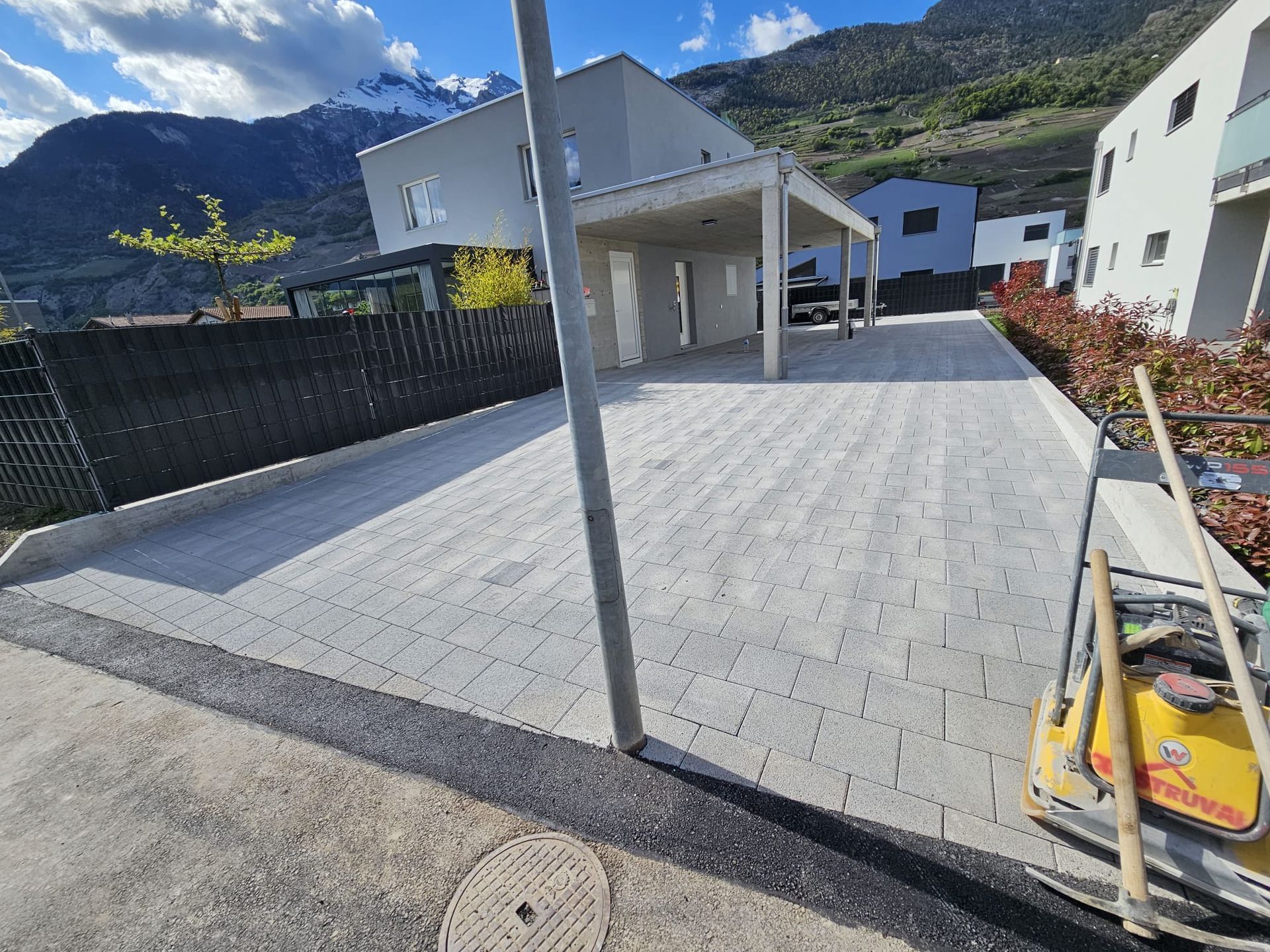 Un homme répand du béton sur un trottoir avec une truelle.