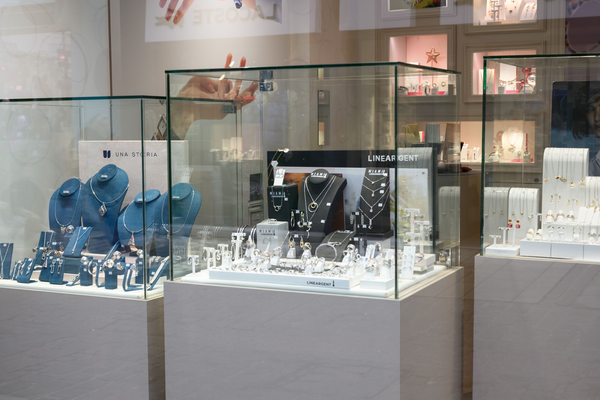 Vitrines de bijouterie remplies de colliers, de bagues et de boucles d'oreilles, éclairées sur des socles blancs.