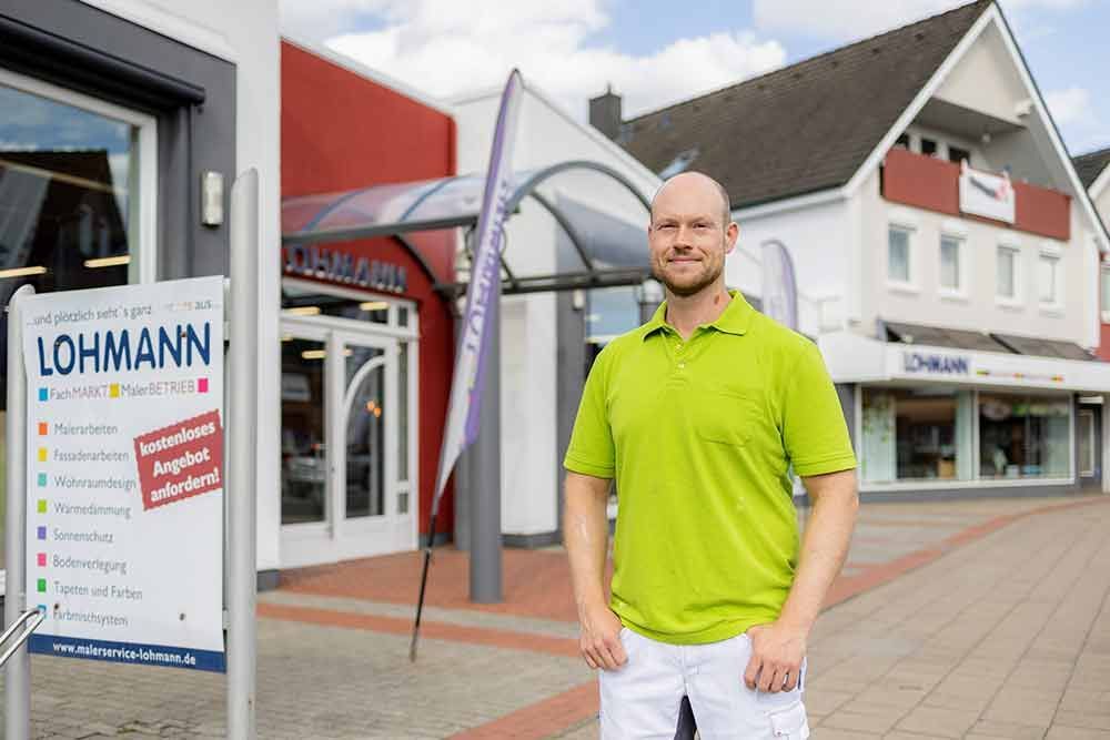 Ein Mann in einem grünen Hemd steht vor einem Gebäude.