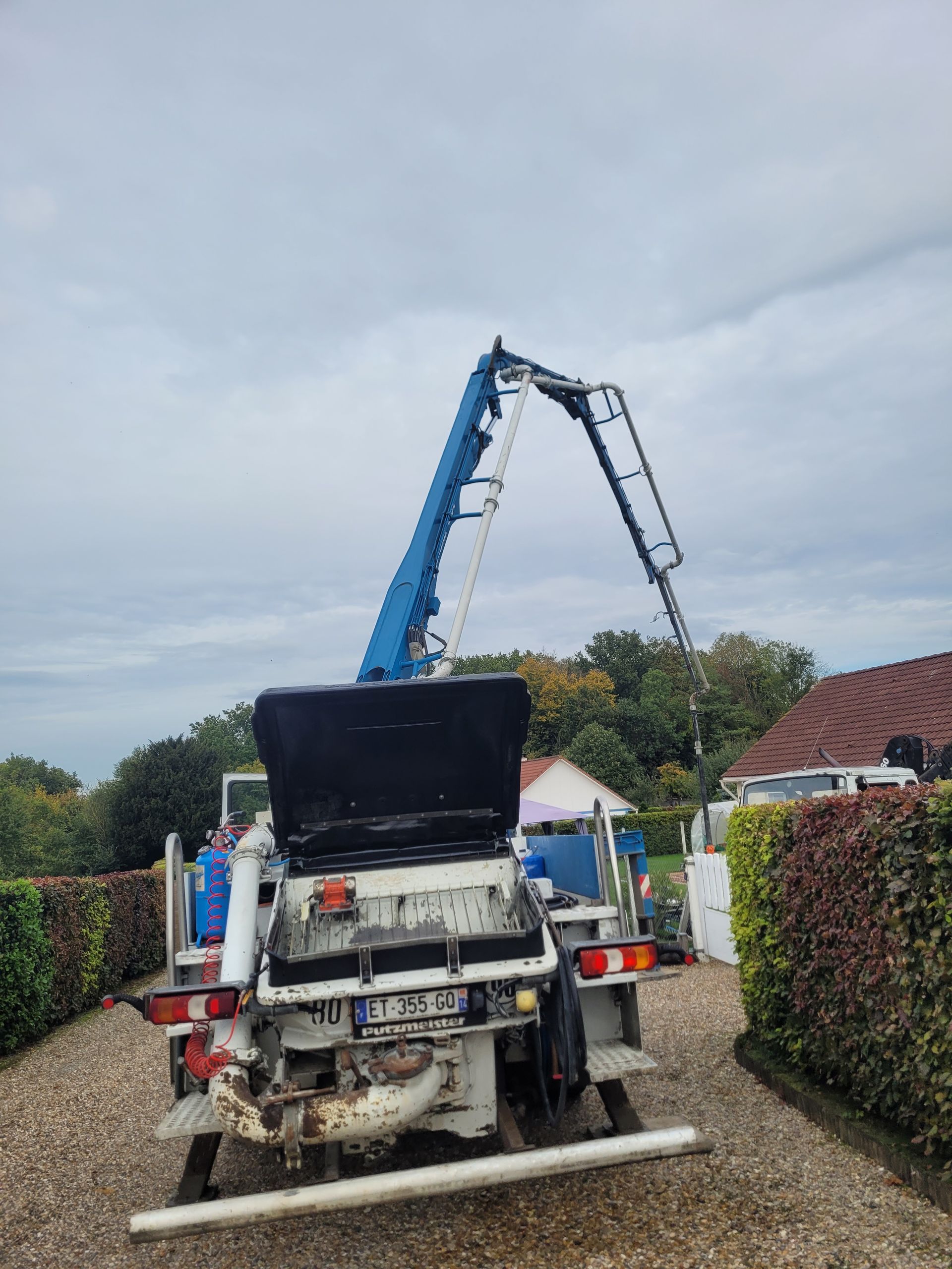 Camion avec bras grue bleu devant une maison individuelle
