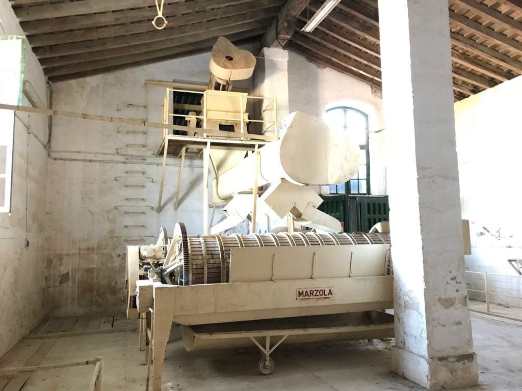 Una máquina antigua de aspecto industrial en una habitación de paredes blancas y techo de madera.