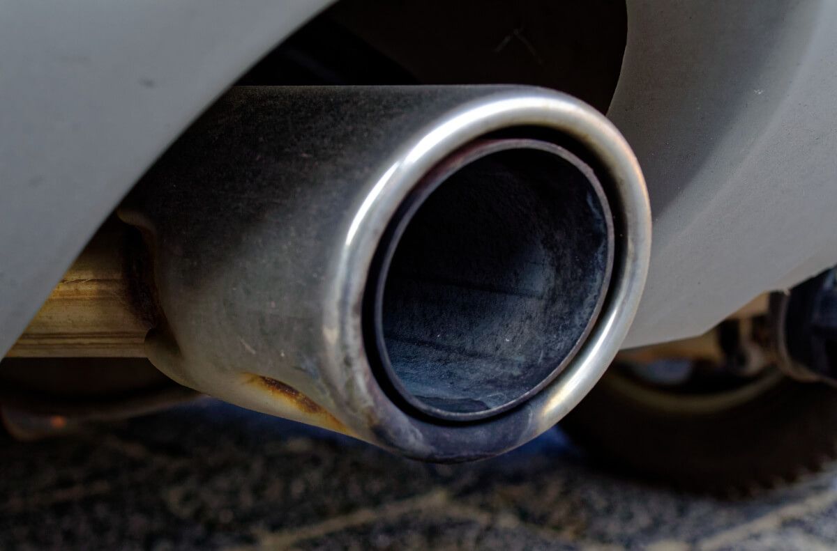 A close up of a car exhaust pipe with smoke coming out of it
