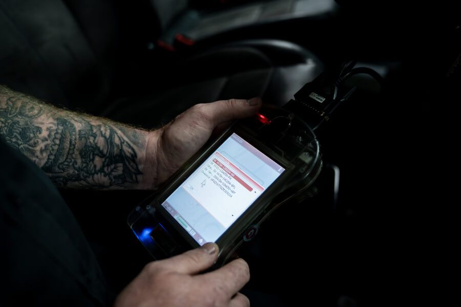A man with a tattoo on his arm is using a tablet in a car.