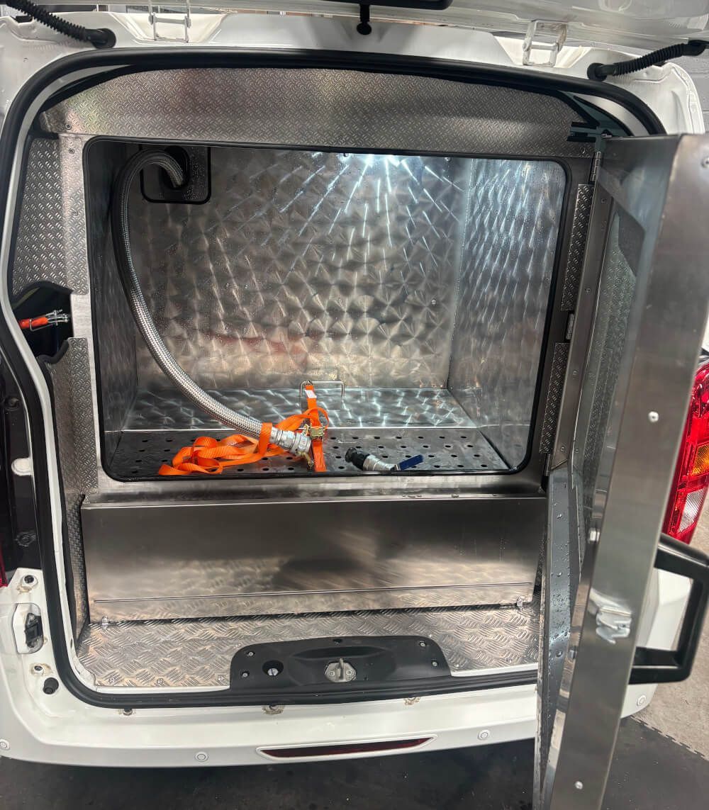 The trunk of a white van with the door open and a hose in it.