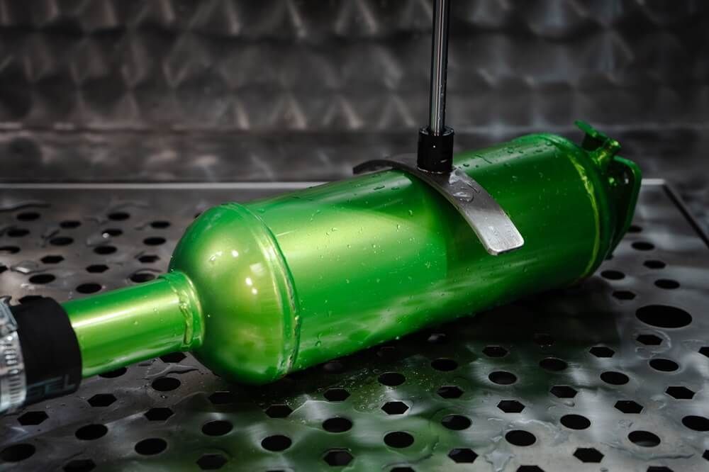 A green bottle is sitting on top of a metal tray.