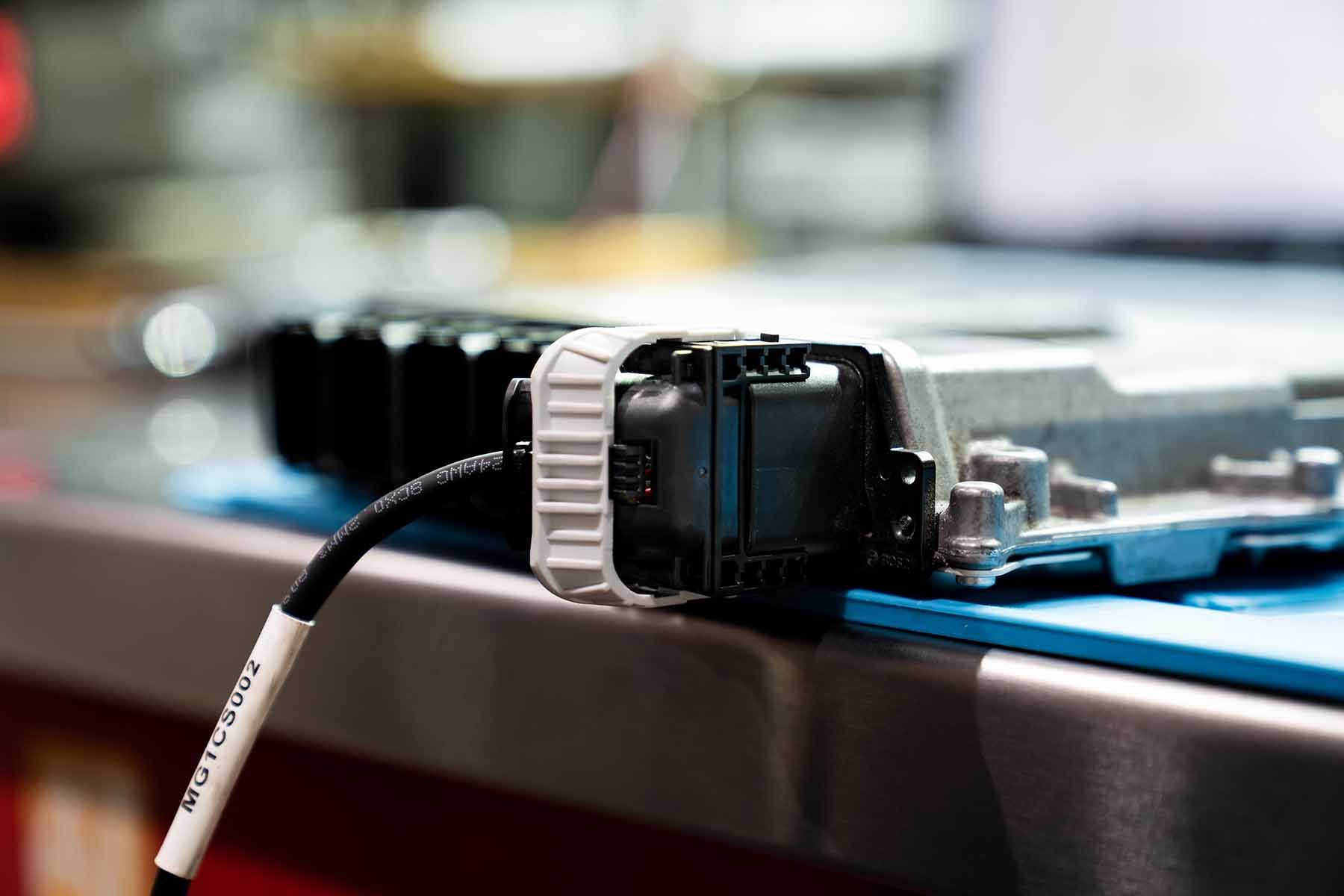 A close up of a cable plugged into a computer on a table.